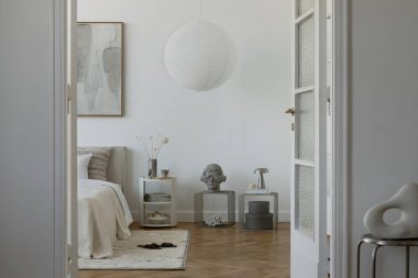 Minimalist yatak odası, sanat, kağıt lamba ve yumuşak bej tonlarda dekoratif aksanlar eşikten görülüyor. Şık iç tasarım.