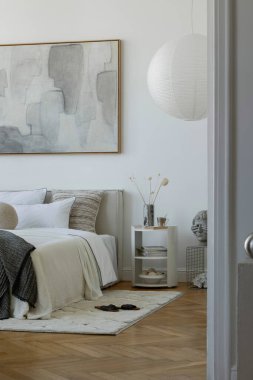 Geniş soyut bir tablo, kağıt fener, katmanlı tekstil ve heykel dekorları olan parlak ve havadar bir yatak odası..