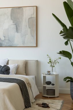 Yumuşak nötr tonları olan parlak minimalist yatak odası yatağın üzerinde büyük soyut resim ve beyaz perdelerin arasından akan doğal ışık..