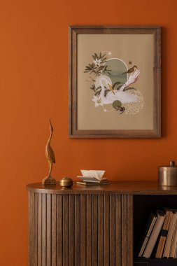 Modern dekorlu ahşap bir dolaba yakın çekim ve turuncu bir duvara poster çerçevesi..
