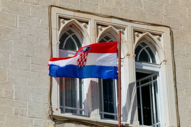 UNESCO 'nun miras kenti Trogir' deki ortaçağ mimarisinin pencerelerinin önünde Hırvat bayrağı dalgalanırken