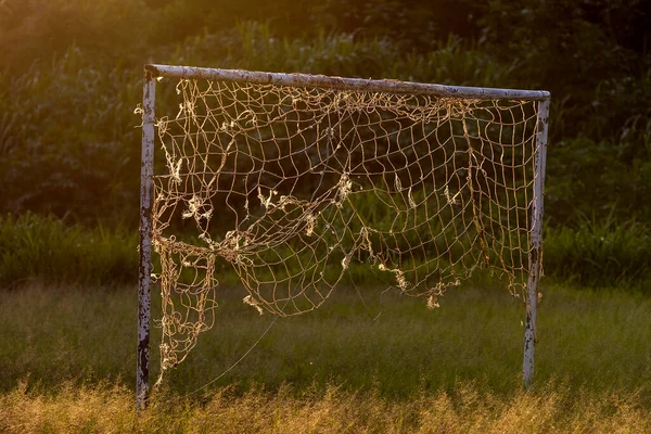 Empty soccer football net on the field in countryside of Sao Paulo state, Brazil with evening sun