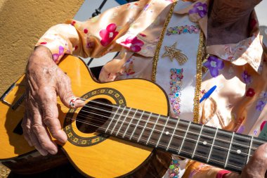 Detail of a gentleman playing the guitar during the Folia de Reis folk festival. Sunny day; colorful clothes clipart