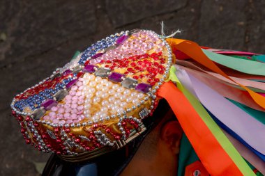 Santa Ifignia kongadasının geleneksel folklorik tezahüratında siyah erkek hatibimizin ziyafetinde kep ve kurdelelerde çok renkli süslemeler var. Sao Paulo Brezilya