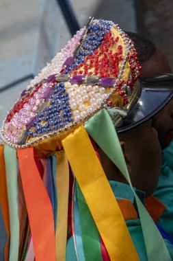Santa Ifignia kongadasının geleneksel folklorik tezahüratında siyah erkek hatibimizin ziyafetinde kep ve kurdelelerde çok renkli süslemeler var. Sao Paulo Brezilya