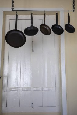 Metal kızartma tavaları eski bir evde asılıydı.