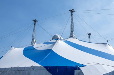 Güneşli gökyüzünün altında büyük mavi ve beyaz sirk çadırı