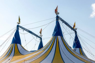 Sirk çadırı mavi, sarı ve beyaz çizgili desenli Brezilya, italyan ve Sao Paulo eyalet bayrağı, mavi gökyüzüne karşı 