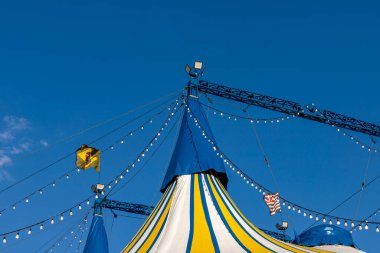 Mavi gökyüzüne karşı Brezilya ve Sao Paulo eyalet bayrağıyla mavi, sarı ve beyaz çizgili sirk çadırı deseni 