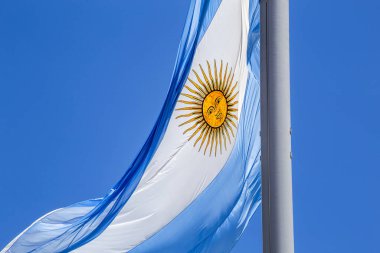 Güneşli bir günde mavi gökyüzünde bayrak direğinde dalgalanan Arjantin bayrağı. Arjantin 'in vatanseverlik sembolü