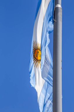 Güneşli bir günde mavi gökyüzünde bayrak direğinde dalgalanan Arjantin bayrağı. Arjantin 'in vatanseverlik sembolü