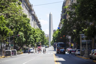 Buenos Aires, Arjantin - 27 Ocak 2024: - Başkan Roque Saenz Pena Caddesi 'nde Karşıdan karşıya geçen yayalar 9 de Julio Caddesi' ndeki Meşhur ve Turistik Obelisk 'e bakıyorlar