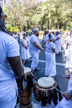 Sao Paulo, Brezilya - Ağustos, 2024 - Hayranlar Avenida Paulista, Sao Paulo şehir merkezinde Candomble partisini kutluyorlar. Ön planda vurmalı çalgıcılar bir Afro-Brezilya davulu çalıyorlar..