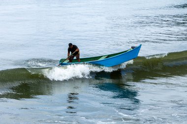 Pereque Sahili, Guaruja, Sao Paulo Eyaleti, Brezilya - Mayıs 2003, 2025 - balıkçı teknesinde kürek çekiyor ve bir günlük balık avından sonra sahile gidiyor.
