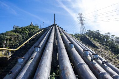 Santos eski yolu, Serra do Mar yolu, hidroelektrik santraline giden su boruları. Arka plandaki yüksek voltaj kulesinde, bir dağ yamacında bakım treni için raylar.