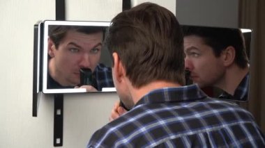 A man hangs a smart mirror on the door. A man shows off his beauty in front of a modern smart mirror. Smart mirror with backlight