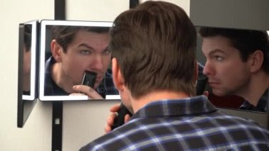 A man hangs a smart mirror on the door. A man shows off his beauty in front of a modern smart mirror. Smart mirror with backlight