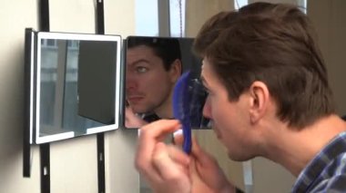 A man hangs a smart mirror on the door. A man shows off his beauty in front of a modern smart mirror. Smart mirror with backlight