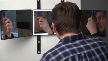 A man hangs a smart mirror on the door. A man shows off his beauty in front of a modern smart mirror. Smart mirror with backlight