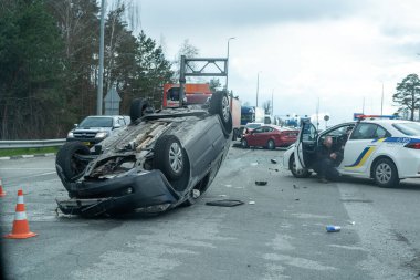 Kyiv bölgesi, Ukrayna - 10 Nisan 2023: Kente yaklaşım sırasında otoyolda devrilen araba. Otobanda bir trafik kazası. Otoyolda arabaları çarpıp devirdiler. Bir polis bir trafik kazasını inceliyor..