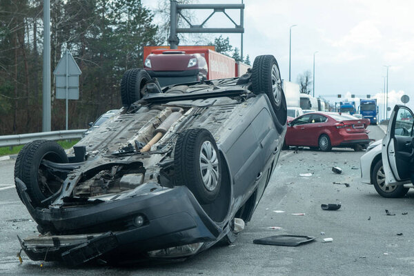 Kyiv region, Ukraine - April 10, 2023: Overturned car on the highway during the approach to the city. Traffic accident on the autobahn. Crashed and overturned cars on the highway. 