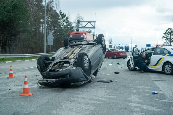Kyiv bölgesi, Ukrayna - 10 Nisan 2023: Kente yaklaşım sırasında otoyolda devrilen araba. Otobanda bir trafik kazası. Otoyolda arabaları çarpıp devirdiler. Bir polis bir trafik kazasını inceliyor..