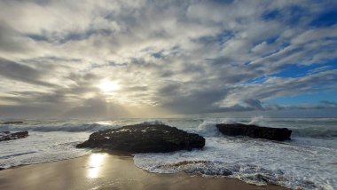 Praia do Magoito, Sintra, Portekiz - Mart 2023: Okyanus manzarası, kayalar, kum ve dalgalar sahilde. Atlantik Okyanusu 