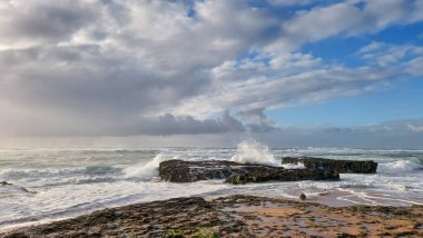 Praia do Magoito, Sintra, Portekiz - Mart 2023: Okyanus manzarası, kayalar, kum ve dalgalar sahilde. Atlantik Okyanusu 