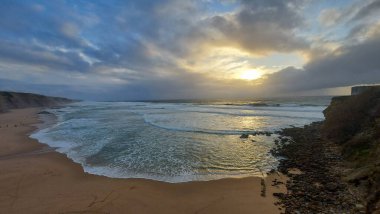 Praia do Magoito, Sintra, Portekiz - Mart 2023: Okyanus manzarası, kayalar, kum ve dalgalar sahilde. Atlantik Okyanusu 
