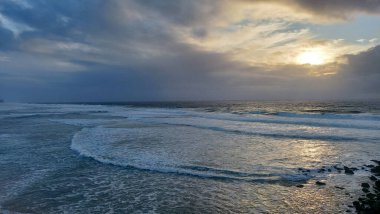 Praia do Magoito, Sintra, Portekiz - Mart 2023: Okyanus manzarası, kayalar, kum ve dalgalar sahilde. Atlantik Okyanusu 