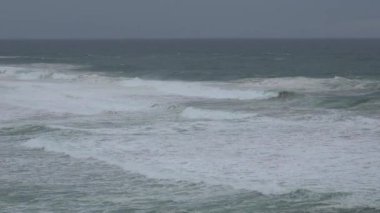 Praia do Magoito, Sintra, Portekiz - Mart 2023: Okyanus manzarası, kayalar, kum ve dalgalar sahilde. Atlantik Okyanusu.