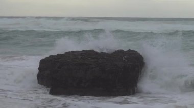 Praia do Magoito, Sintra, Portekiz - Mart 2023: Okyanus manzarası, kayalar, kum ve dalgalar sahilde. Atlantik Okyanusu.