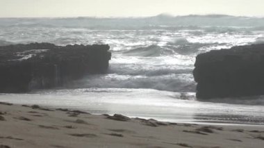 Praia do Magoito, Sintra, Portekiz - Mart 2023: Okyanus manzarası, kayalar, kum ve dalgalar sahilde. Atlantik Okyanusu.