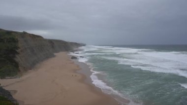 Praia do Magoito, Sintra, Portekiz - Mart 2023: Okyanus manzarası, kayalar, kum ve dalgalar sahilde. Atlantik Okyanusu.