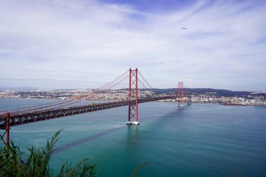 Lizbon, Portekiz - Mart 2023: 25 Nisan Köprüsü ve Lizbon şehri manzarası. 25 de Abril Köprüsü.