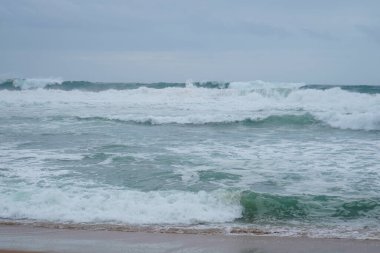 Praia do Magoito, Sintra, Portekiz - Mart 2023: Okyanus manzarası, kayalar, kum ve dalgalar sahilde. Atlantik Okyanusu