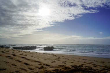 Praia do Magoito, Sintra, Portekiz - Mart 2023: Okyanus manzarası, kayalar, kum ve dalgalar sahilde. Atlantik Okyanusu