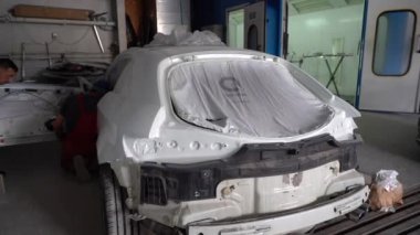 Kyiv, Ukrayna - 12 Ağustos 2023: Araba tamirhanesinde boyacı. Boya atölyesi müdürü. Boya kabinine araba boyamak. Resim yaptıktan sonra parçalanmış araba.