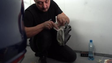 Kyiv, Ukrayna - 12 Ağustos 2023: Araba tamirhanesinde boyacı. Boya dükkanının sahibi arabayı boyama için hazırlar. Boya kabininde araba boyamak..