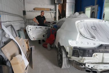 Kyiv, Ukrayna - 12 Ağustos 2023: Araba tamirhanesinde boyacı. Boya dükkanının sahibi arabayı boyama için hazırlar. Boya kabininde araba boyamak..