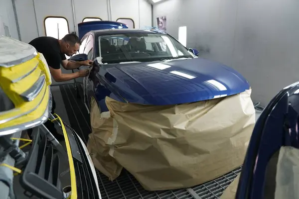 Kyiv, Ukraine - August 12, 2023: Paint shop at the car service station. The master of the paint shop prepares the car for painting. Painting a car in a paint booth.