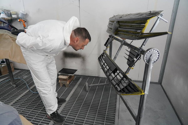 Киев, Украина - 12 августа 2023 года: Магазин красок на автосервисе. Хозяин лакокрасочного цеха красит машину. Картина автомобиля в лакокрасочной кабинке.