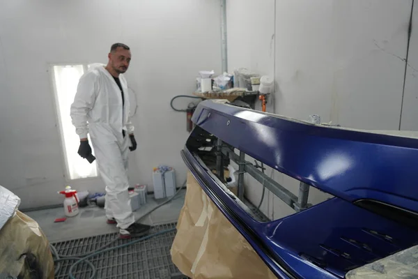 Kyiv, Ukraine - August 12, 2023: Paint shop at the car service station. The master of the paint shop paints the car. Painting a car in a paint booth.