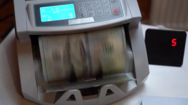 Banknotlar için sayma makinesi. Ukrayna banknot sayma makinesi. Amerikan parası sayım makinesinde. Para birimi dönüşümü. Amerikan dolarları bir banknot makinesi tarafından sayılır. Bir yığın yüzlük.