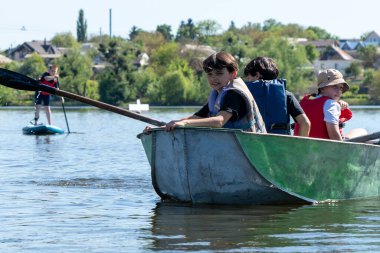 Ukrayna, Bila Tserkva, Kyiv Bölgesi - 01 Mayıs 2024: Şehrin orta kesimindeki gölde çocuklar kürek çekiyor. Tekne ile ilgili spor sayfası.
