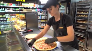 Kyiv bölgesi, Ukrayna - 16 Eylül 2024: Pizzacı kız pizza hazırlıyor. Kafenin mutfağında pizza üretimi..