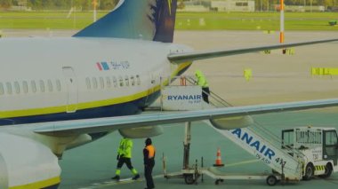 Krakow, Polonya - 20 Ekim 2024 Krakow Havaalanı. Kalkıştan önce uçak kontrolleri (biniş). Havaalanı çalışanı uçağa servis yapıyor. Bagaj yükleme (boşaltma). Yolcular (varış). Ryanair