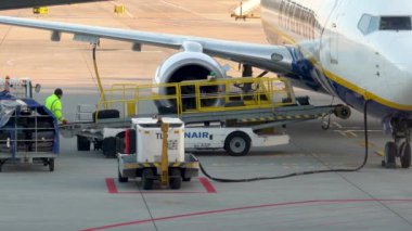 Krakow, Polonya - 20 Ekim 2024 Krakow Havaalanı. Kalkıştan önce uçak kontrolleri (biniş). Havaalanı çalışanı uçağa servis yapıyor. Bagaj yükleme (boşaltma). Yolcular (varış). Ryanair