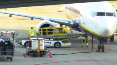 Krakow, Polonya - 20 Ekim 2024 Krakow Havaalanı. Kalkıştan önce uçak kontrolleri (biniş). Havaalanı çalışanı uçağa servis yapıyor. Bagaj yükleme (boşaltma). Yolcular (varış). Ryanair