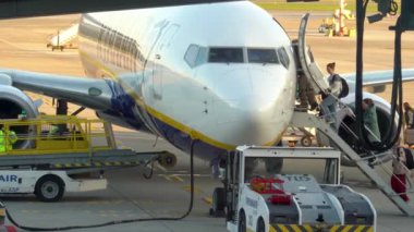 Krakow, Polonya - 20 Ekim 2024 Krakow Havaalanı. Kalkıştan önce uçak kontrolleri (biniş). Havaalanı çalışanı uçağa servis yapıyor. Bagaj yükleme (boşaltma). Yolcular (varış). Ryanair